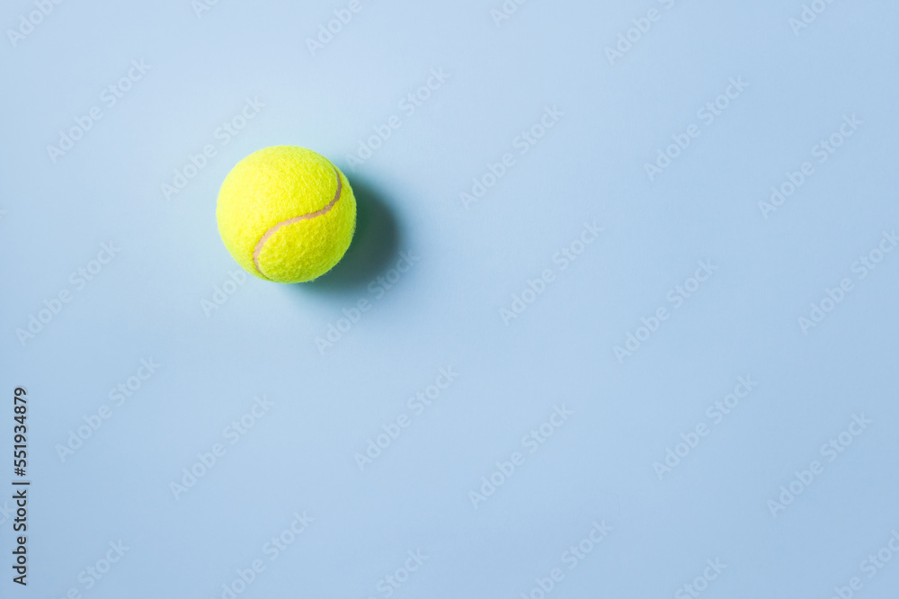 Tennis ball as myofascial release equipment for trigger points on blue background. Minimal concept of MFR, self-massage and physiotherapy. Selective focus, copy space