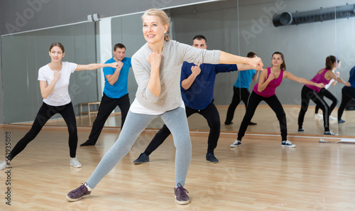 Portrait of dancing mature woman practicing vigorous swing during group training in dance studio