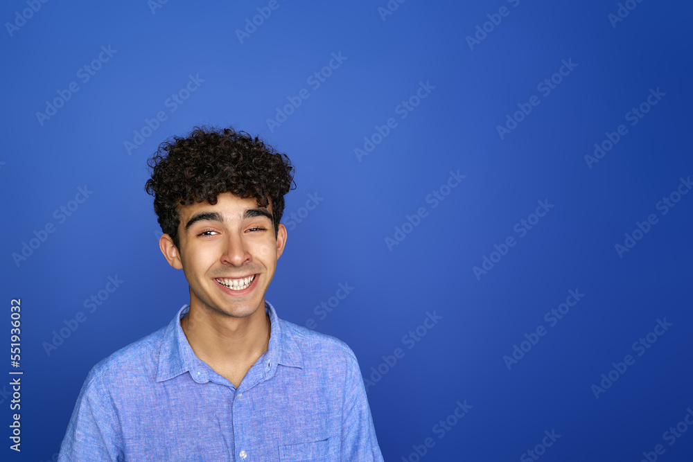 Obraz premium Smiley teenager looks excited, isolated on a blue background.