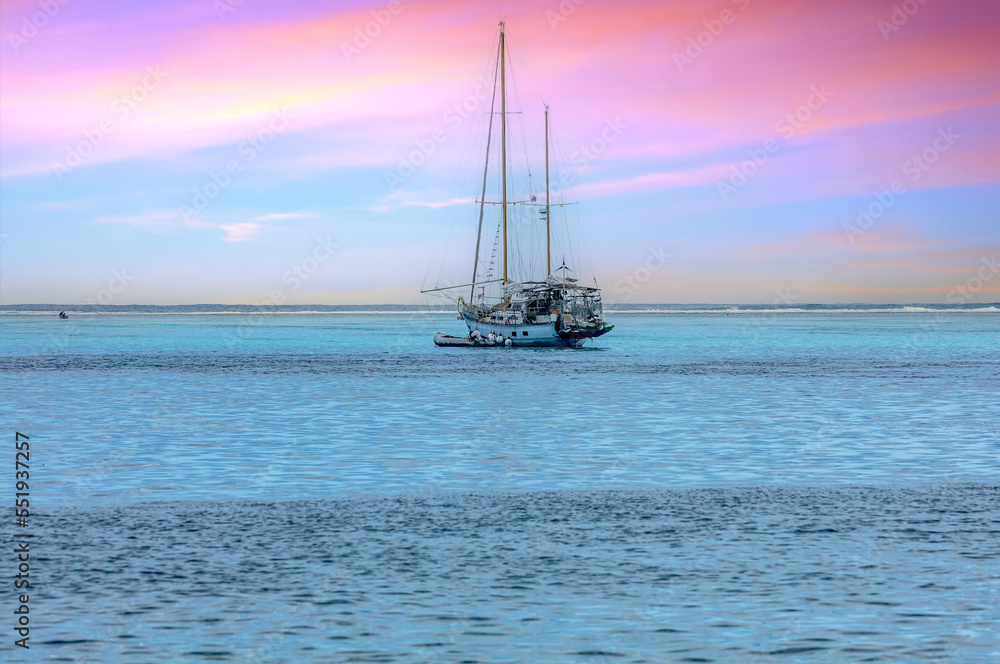 Fototapeta premium bateau voilier au Coucher de soleil rose et lagon bleu turquoise de Polynésie