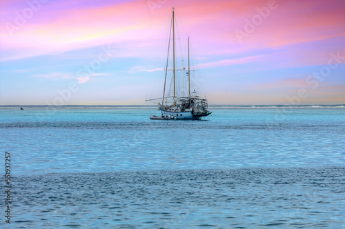 bateau voilier au Coucher de soleil rose et lagon bleu turquoise de Polynésie