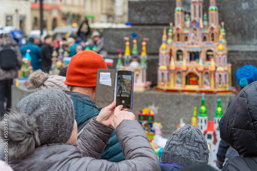 Spectators shoot on smartphones the annual creative competition of miniature models of Krakow sights on the eve of Christmas, shopka - a traditional exhibition of handicrafts in the center of Krakow
