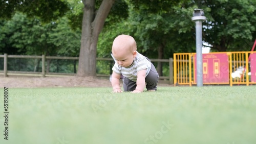 Happy family having picnic. Little Baby is crawling on green grass. Summer in park. Siblings children Playing in green park. Family fun and joy in Playgroung. Active son crawls barefoot in the field