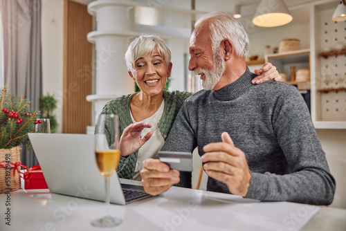 an embracing elderly couple shopping online for Christmas