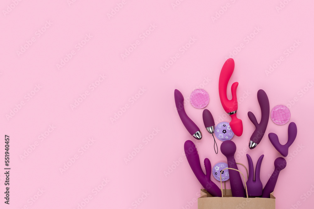 A paper shopping bag filled pink Purple silicone sex toys on a white background. Erotic toy for fun. Sex gadget and masturbation device. View from above. Place for text. Flat lay. Sex shop concept. - obrazy, fototapety, plakaty 