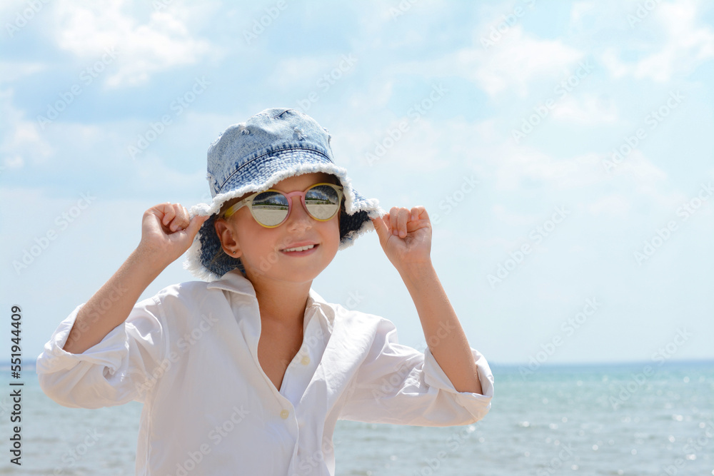 Little girl wearing sunglasses and hat at beach on sunny day. Space for text Little girl wearing sunglasses and hat at beach on sunny day. Space for text