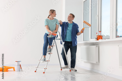 Happy couple discussing interior details in apartment during repair