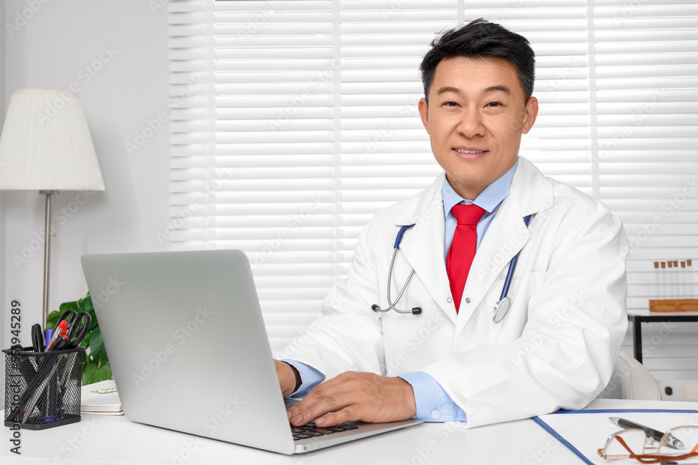 Happy doctor with laptop consulting patient at white desk in clinic. Online medicine Happy doctor with laptop consulting patient at white desk in clinic. Online medicine