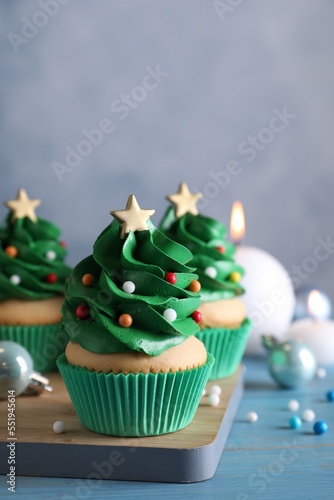 Christmas tree shaped cupcakes and decor on light blue wooden table