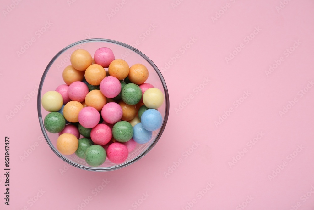 Bowl with many bright gumballs on pink background, top view. Space for text Bowl with many bright gumballs on pink background, top view. Space for text