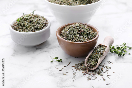 Bowls and scoop with dried thyme on white marble table, closeup