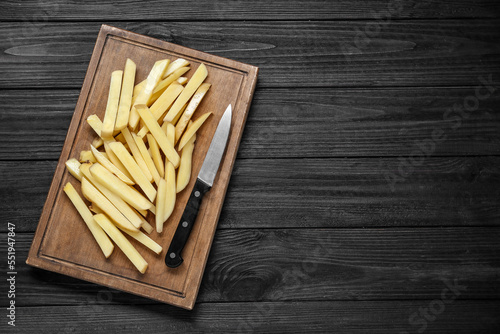 Cut raw potatoes on black wooden table, top view. Space for text