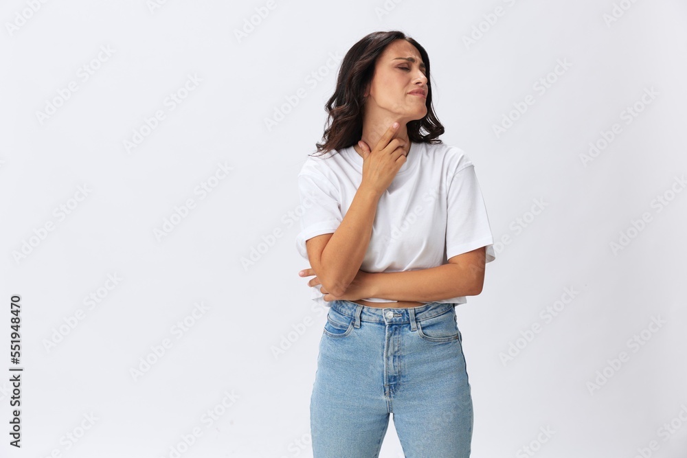 Woman sore throat and inflammation of the ligaments with a cold, a woman in a white t-shirt and jeans on a white background, copy space Woman sore throat and inflammation of the ligaments with a cold, a woman in a white t-shirt and jeans on a white background, copy space