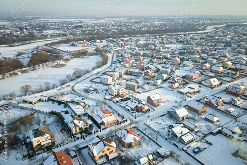 Aerial view of residential houses with snow covered roofops in suburban rural town area in winter © bilanol