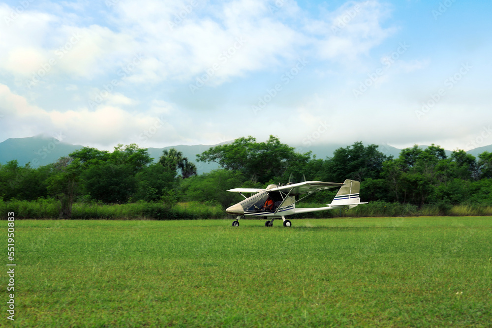 Light aircraft on grass near trees and mountains Light aircraft on grass near trees and mountains
