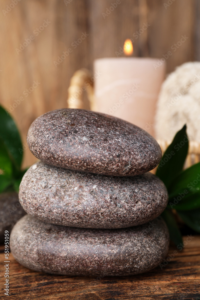 Stacked spa stones, bamboo leaves and candle on wooden table, closeup Stacked spa stones, bamboo leaves and candle on wooden table, closeup
