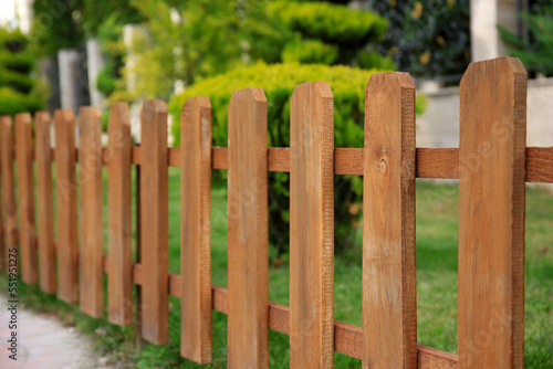 Closeup view of small wooden fence near green bushes in garden