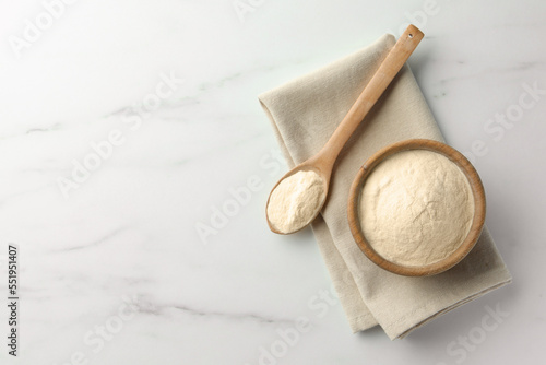 Bowl and spoon of agar-agar powder on white marble table, flat lay. Space for text