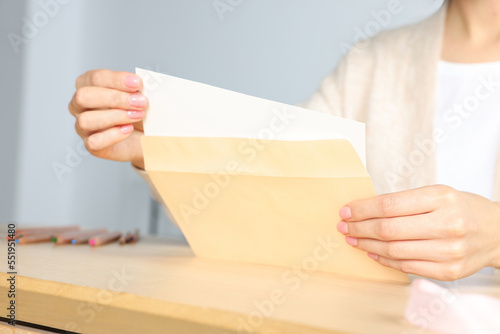 Woman holding greeting card at wooden table, closeup