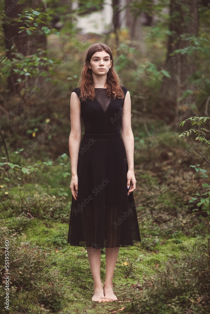 beautiful girl in the forest A young woman in a black dress balancing barefoot in the forest on covered with moss. Forest therapy concept. beautiful girl in the forest A young woman in a black dress balancing barefoot in the forest on covered with moss. Forest therapy concept.