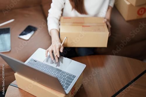 Starting small business entrepreneur of independent young Asian woman online seller is using computer and taking orders to pack products for delivery to customers. SME delivery concept