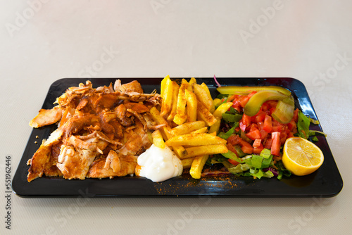 Turkish and Arabic Traditional Ramadan doner kebab with tasty tomato sauce and rice or turkish pilav in white plate on wood table background. ( Pilav ustu doner) photo