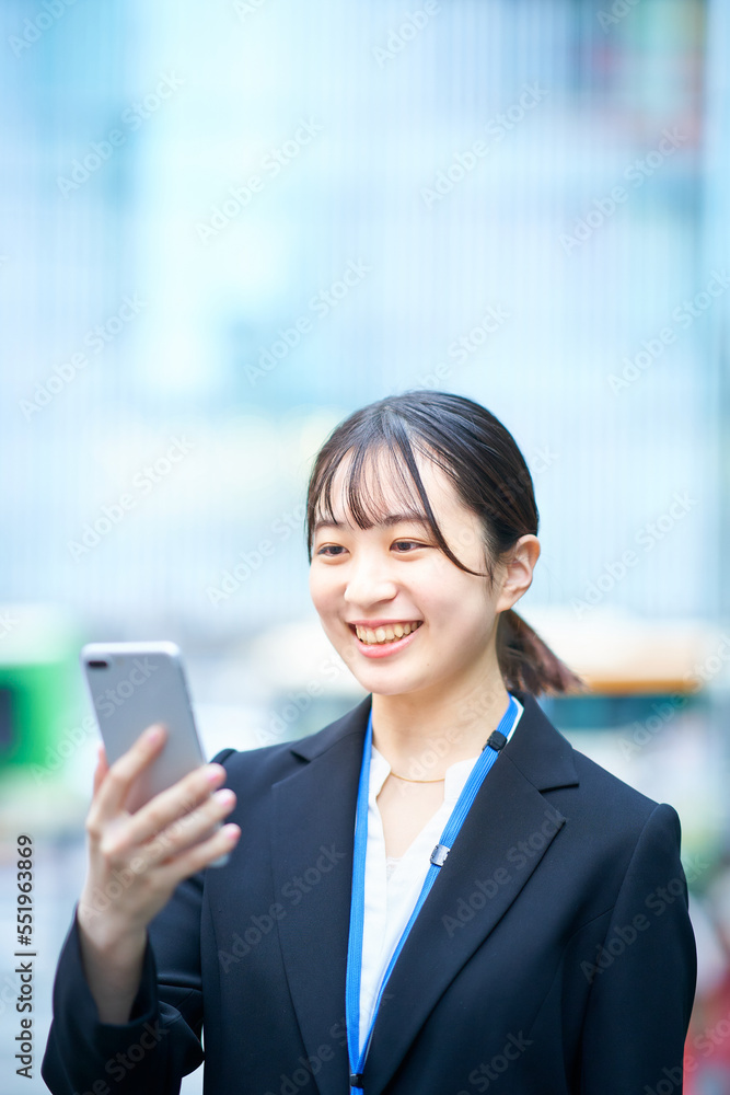 スマートフォンの画面を見るスーツ姿の若い女性