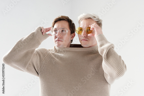 Cool Siamese brothers wearing one big sweater putting on stylish eyeglasses waist up portrait photo
