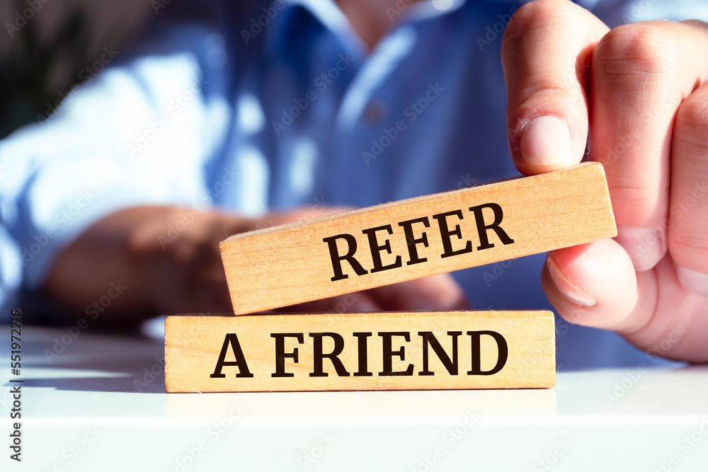 Refer a friend text concept written on wooden blocks lying on a table