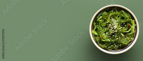 Bowl with healthy seaweed salad on green background with space for text photo