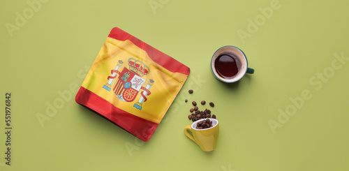 Cups with aromatic coffee and bag with print of Spanish flag on green background