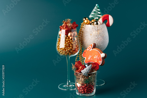 Glass cups with Christmas decor against dark green background
