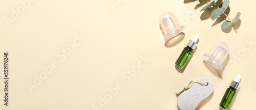 Composition with bottles of essential oil, pumice and vacuum jars for anti-cellulite massage on color background with space for text