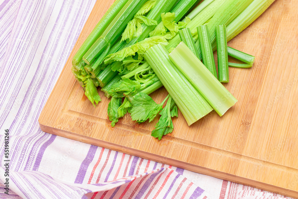 Fresh Celery Stem and Chopped Celery Sticks on Wooden Cutting Board. Vegan and Vegetarian Culture. Raw Food. Healthy Diet with Negative Calorie Content. Slimming Food