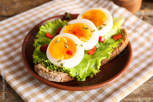 Plate of delicious toast with boiled egg on wooden table, closeup