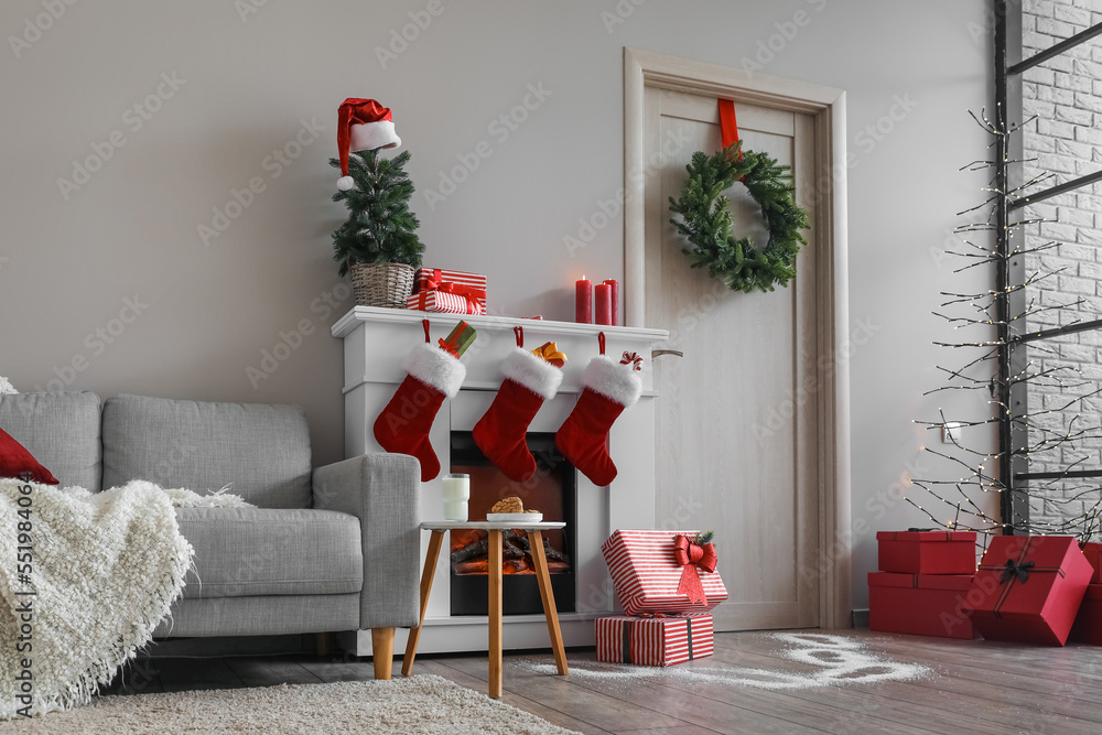 Obraz premium Interior of living room with wooden door, fireplace, sofa and Christmas decor