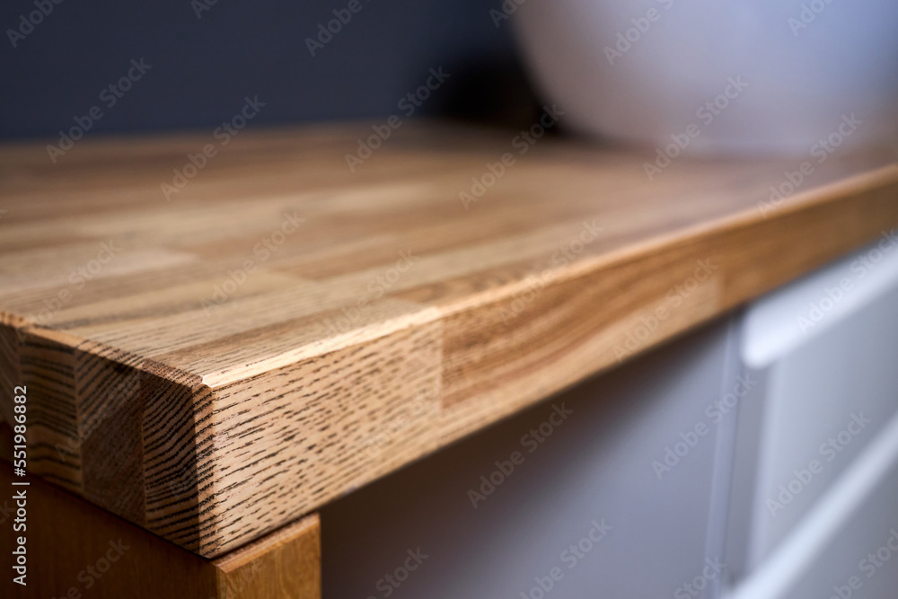 Solid ash glued timber corner table top closeup. Bathroom interior contemporary design countertop tabletop with sink.