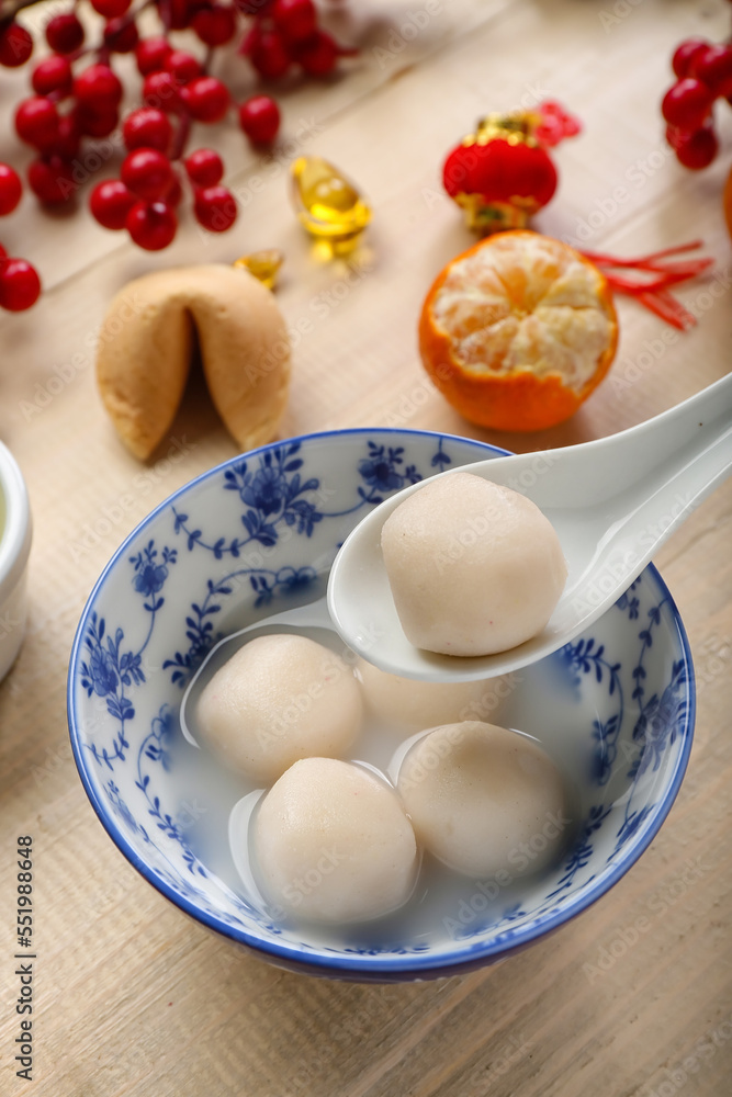 Spoon and bowl of tangyuan on wooden background, closeup. Dongzhi Festival Spoon and bowl of tangyuan on wooden background, closeup. Dongzhi Festival