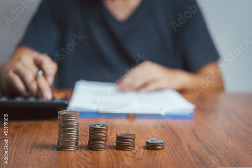 businessman saving money and coins stacking on desk with note for planning money finance concept. Business financial investment and tax, accounting.