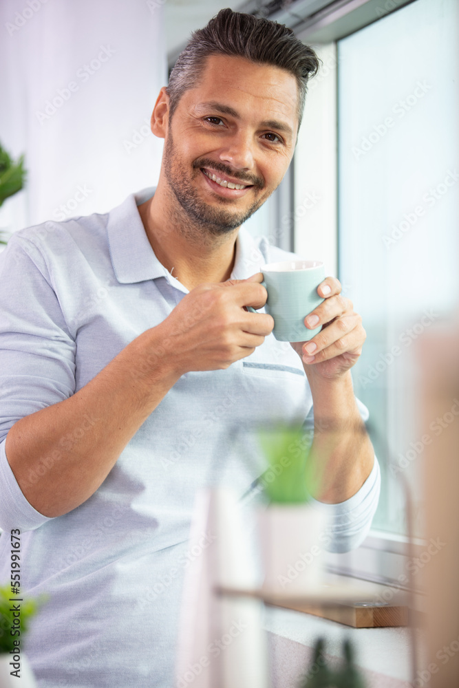 man holding a coffee cup beside a window man holding a coffee cup beside a window