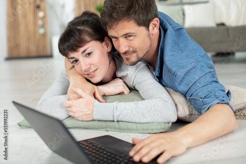 couple doing online shopping at home using laptop on floor