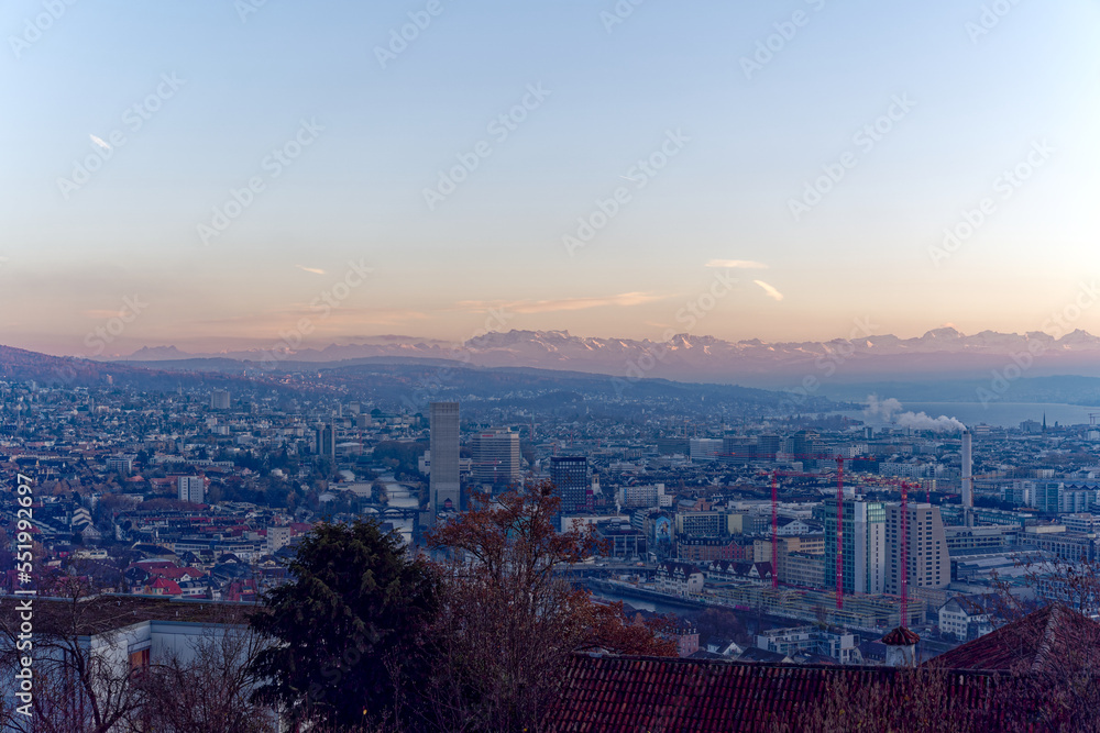 Naklejka premium Aerial view over City of Zürich with Limmat River and Swiss Alps in the background on a sunny autumn evening. Photo taken December 6th, 2022, Zurich, Switzerland.