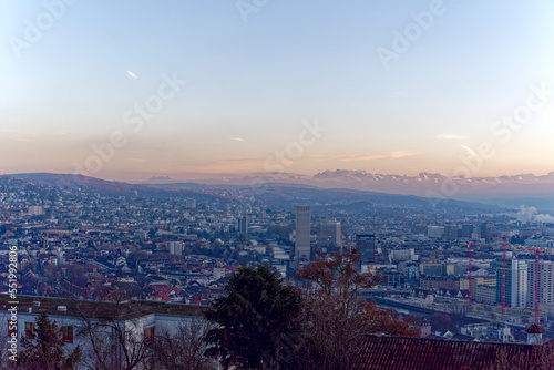 Aerial view over City of Zürich with Limmat River and Swiss Alps in the background on a sunny autumn evening. Photo taken December 6th, 2022, Zurich, Switzerland. © Michael Derrer Fuchs
