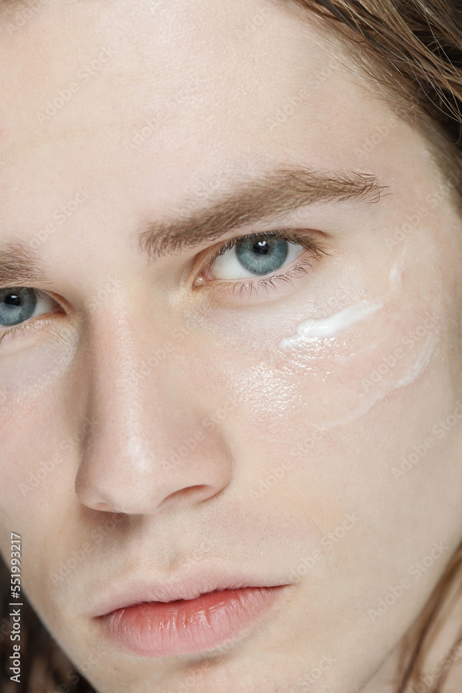 Close up beauty portrait shot of young male model with cream smear on his cheekbone Close up beauty portrait shot of young male model with cream smear on his cheekbone