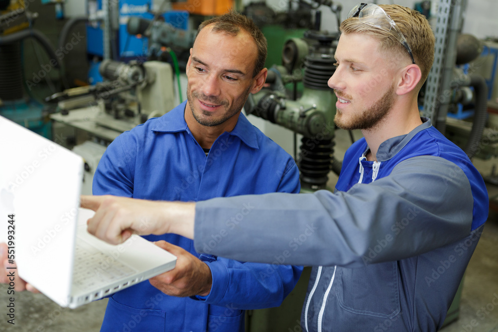 Obraz premium engineers in workshop looking at laptop