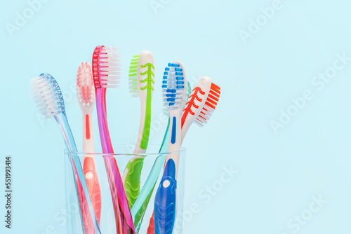 Toothbrushes in glass cup on blue background close-up  copy space.