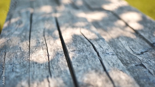 An old wooden table in a summer garden with rays of sunshine.