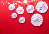 White paper rosettes on  red textured  paper background.  Handmade nordic decoration. Natural, ogranic materials. Place for text. Top view.