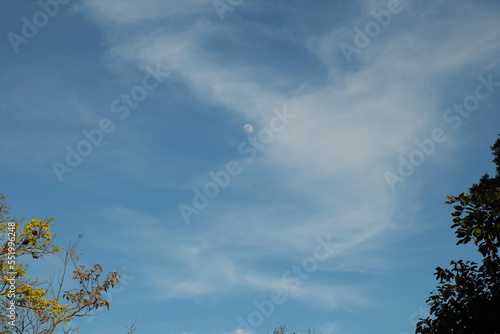 Beautiful blue sky and fluffy cloud landscape background. Moon during the day, full face of the Moon reflecting sunlight. 
