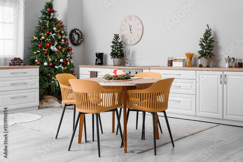 Interior of kitchen with Christmas trees  white counters and dining table